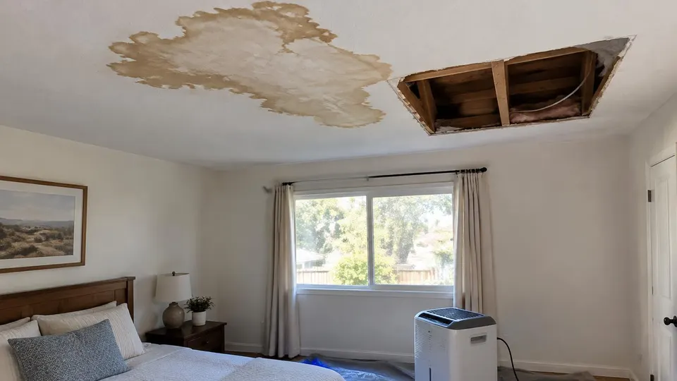 Generated illustration of a stained bedroom ceiling with a section of drywall cut open and a dehumidifier below